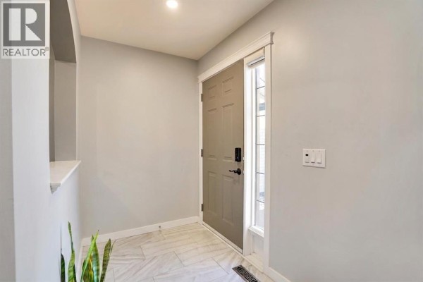 Narrow walkway between two houses with beige siding, leading to a covered outdoor staircase to a basement entrance. - 91 Copperstone Gate Se, Calgary