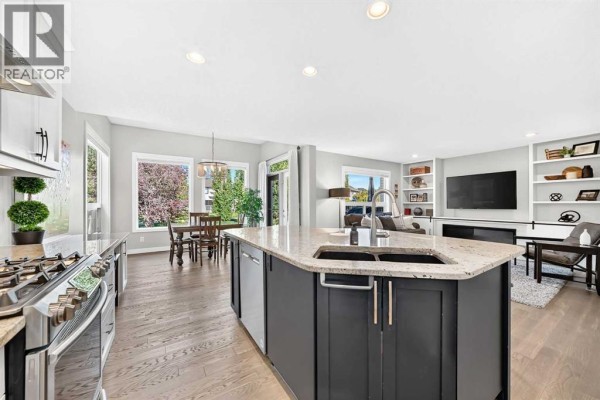 Open concept kitchen and living area with a large island, dining table, and a fireplace. - 91 Cranfield Circle Se, Calgary