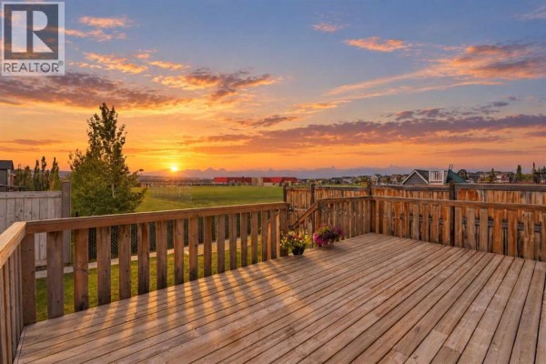 Aerial view of the red house's backyard with a wooden deck and green lawn. - 91 Evansfield Rise Nw, Calgary