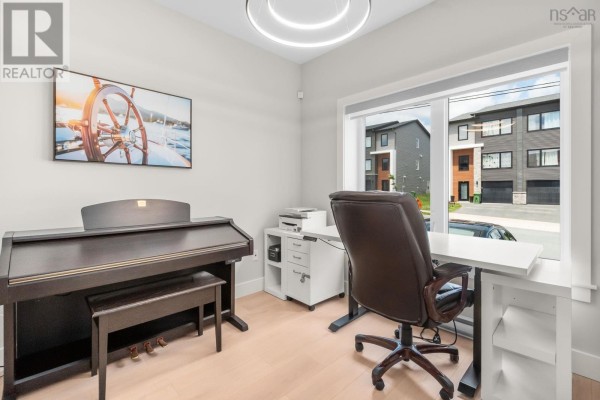 Home office with a piano, desk, chair, and window overlooking the street. - 91 Honeygold Drive, Halifax