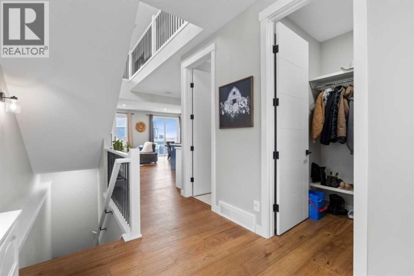 Hallway on the main floor with a staircase, dark railings, and a view into a living area. - 91 North Bridges Road, Langdon