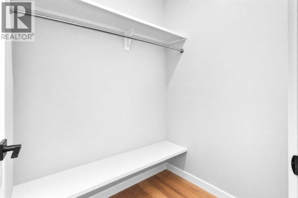 Empty walk-in closet with a single shelf, a hanging rod, and a wooden floor. - 91 North Bridges Road, Langdon