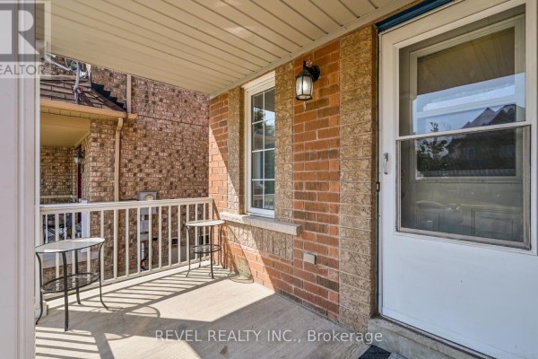 Covered front porch with brick exterior, white railings, and two small metal tables. - 91 Oceanpearl Crescent, Whitby