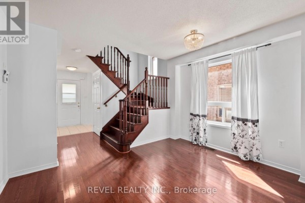 Living room with dark hardwood floors, dark wood staircase, and large window with patterned curtains. - 91 Oceanpearl Crescent, Whitby