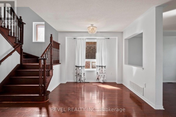 Interior view of staircase and living area with dark hardwood floors and white walls. - 91 Oceanpearl Crescent, Whitby