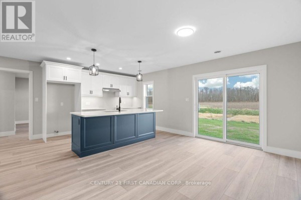 Modern kitchen with blue island and white cabinets, sliding glass doors - 91 Victoria Avenue E South Huron