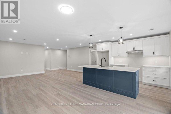 Modern kitchen with blue island, white cabinets, and light wood floors - 91 Victoria Avenue E South Huron