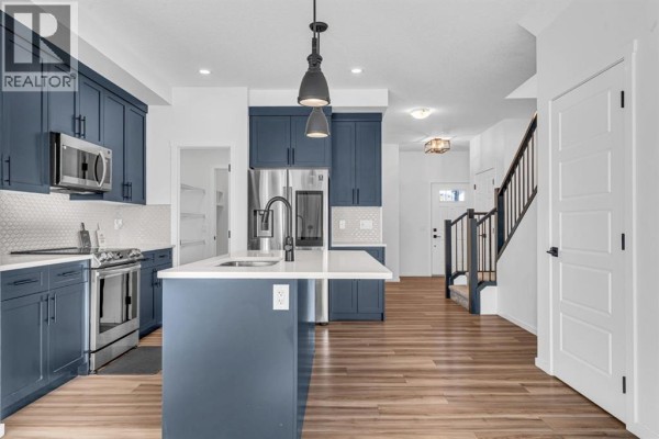 Open concept kitchen and living area with dark cabinets and red bar stools. - 91 Walcrest Way Se, Calgary