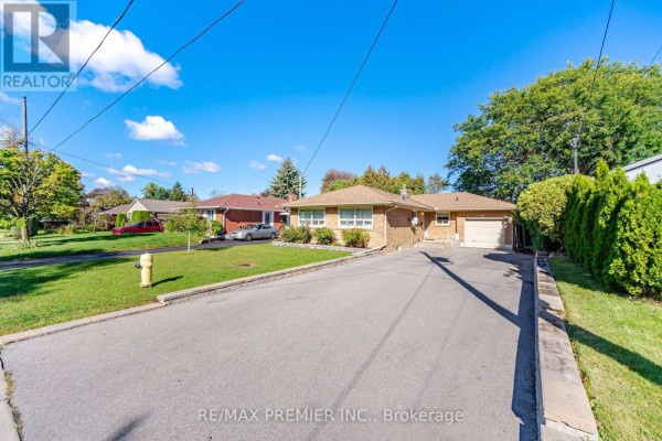 Long paved driveway leading to the front entrance and garage of the brick bungalow. - 91 Wigmore Drive, Toronto