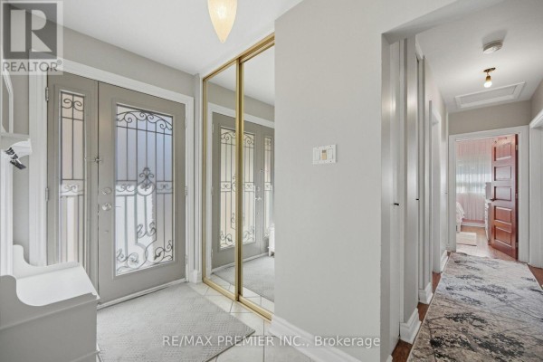 Interior view of a bright hallway with mirrored closet doors, a grey bench, and a patterned rug. - 91 Wigmore Drive, Toronto