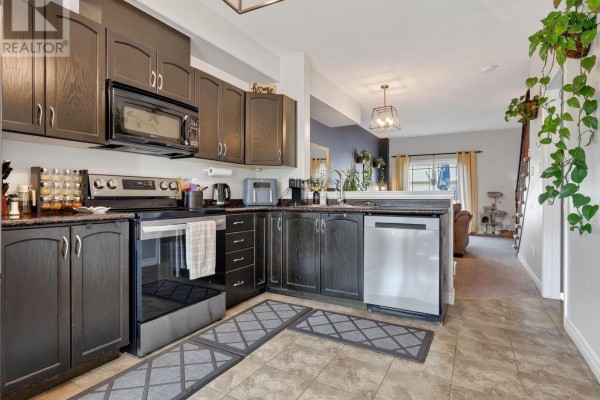 Dark wood kitchen cabinetry, stainless steel appliances including a refrigerator, oven, and dishwasher, and granite countertops. - 91 Willow Lane, Grimsby