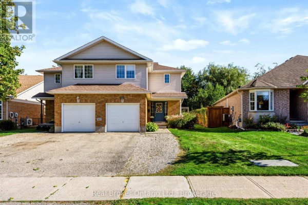 Front exterior view of a duplex with a green lawn, mature trees, and a clear blue sky. - 91 York Street E, Centre Wellington
