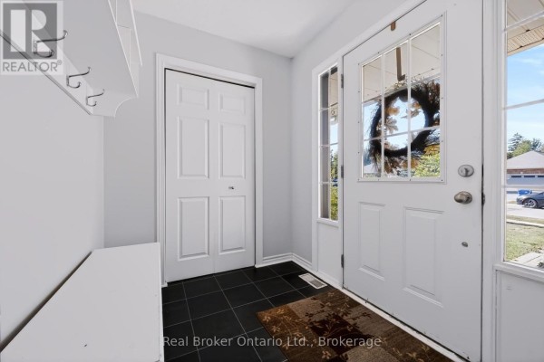 Interior entryway with white doors, a bench, coat hooks, dark tile flooring, and a glass-paneled front door. - 91 York Street E, Centre Wellington
