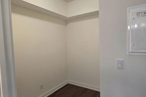 Empty room with beige walls, a white ceiling, and dark laminate flooring. - 910 - 2825 Jane Street, Toronto