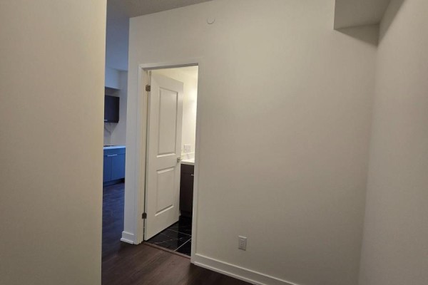 View from a hallway into an open doorway revealing a small bathroom with dark tiled floor. - 910 - 2825 Jane Street, Toronto