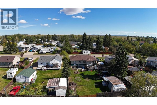 Spacious open-concept kitchen and dining area overlooking a living room with grey sofas. - 9108 8 Street, Dawson Creek