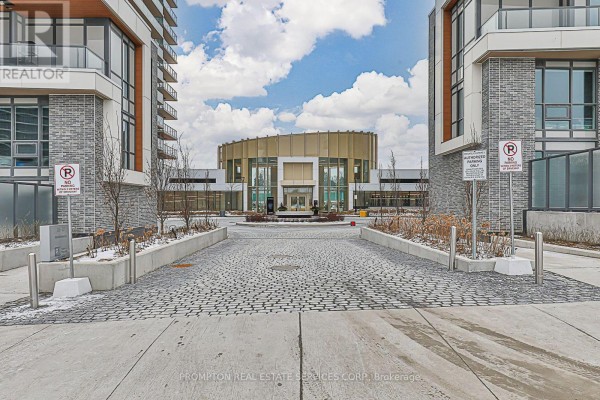Cobblestone driveway leading to the entrance of a modern apartment complex with glass building facades. - 911 - 25 Mcmahon Drive, Toronto
