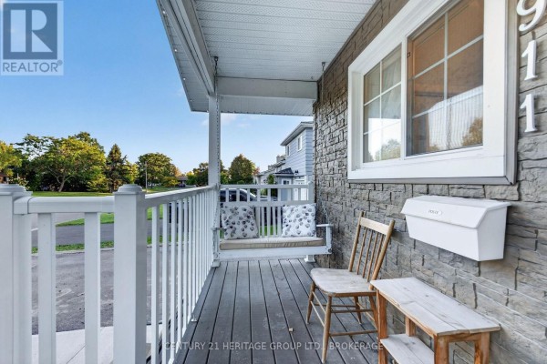 Covered porch with a white swing seat, wood floor, and stone exterior wall. - 911 Auden Park Drive, Kingston