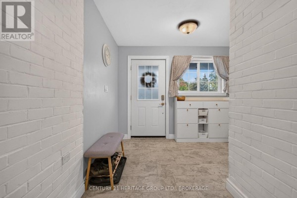 Foyer with light grey walls, white brick accent wall, and beige tile floor. - 911 Auden Park Drive, Kingston