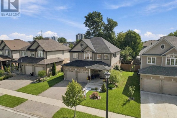 Aerial view of a two-story house with a double garage, manicured lawn, and surrounding homes. - 911 Foxcreek Road, London North