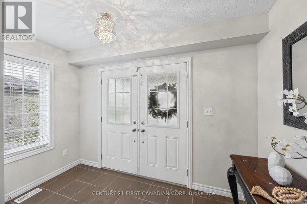 Interior view of a foyer with double glass doors, a window, and brown tile flooring. - 911 Foxcreek Road, London North