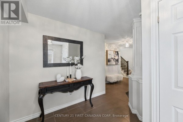 Interior view of a foyer with a console table, mirror, and a view of the staircase. - 911 Foxcreek Road, London North