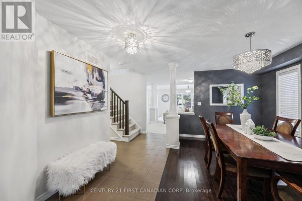Interior view of a dining room and foyer with a dining table, chandelier, staircase, and artwork. - 911 Foxcreek Road, London North