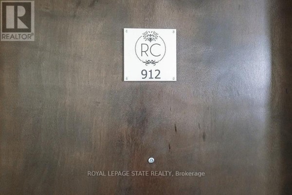 Close-up of apartment door 912 with a decorative sign and polished wood finish. - 912 - 112 King Street E, Hamilton