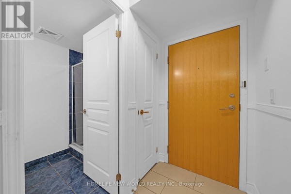 Hallway with a wooden front door and a closed door leading to a bathroom with blue tiled shower. - 912 - 55 South Town Centre Boulevard, Markham