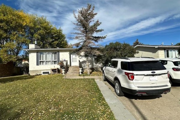 Kitchen with white cabinets, black countertops, and a dining table with a red tablecloth. - 9120 96 Avenue, Lac La Biche