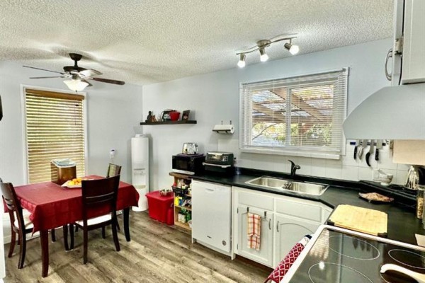 Corner kitchen with white cabinets, a dishwasher, oven, and light wood plank flooring. - 9120 96 Avenue, Lac La Biche