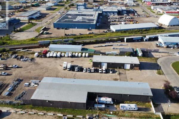 Aerial view of multiple commercial buildings, outdoor storage, and parked vehicles. - 9124 111 Street, Grande Prairie