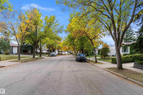 Street view of a suburban neighborhood with houses, sidewalks, and trees showing autumn foliage. - 9126 92 Av, Fort Saskatchewan