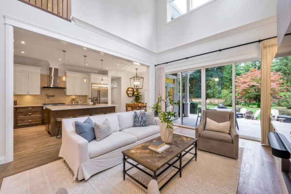 Living room with fireplace, white sofa, and view into open-concept kitchen. - 9128 Edal Street, Langley