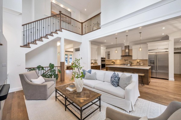 Living room with fireplace, white sofa, and open view to kitchen and staircase. - 9128 Edal Street, Langley