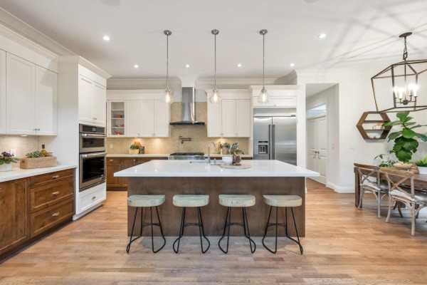Kitchen with large island, white countertops, stainless steel appliances, and wood cabinetry. - 9128 Edal Street, Langley