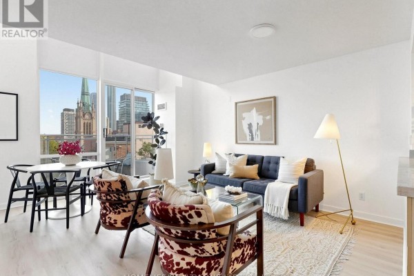 Living room with navy sofa, patterned chairs, and city view. - 913 - 77 Lombard Street, Toronto