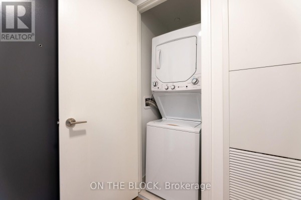White stacked washer and dryer behind a closed white door. - 913 - 86 Dundas Street E, Mississauga