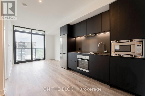 Open concept living area and kitchen with floor-to-ceiling windows and dark cabinetry. - 913 - 86 Dundas Street E, Mississauga