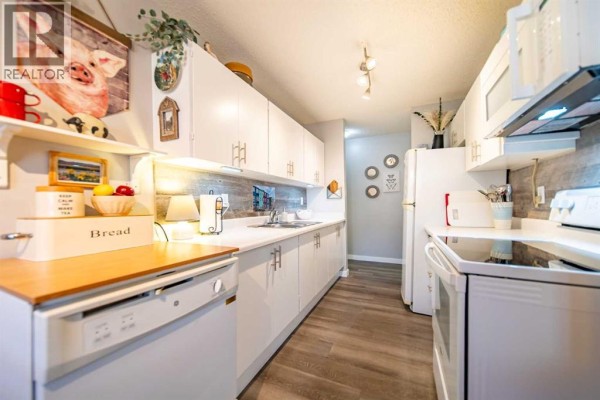 L-shaped kitchen with white cabinets, stainless steel appliances, and a dishwasher. - 914, 11620 Elbow Drive Sw, Calgary