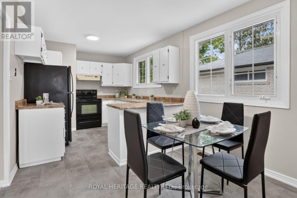 Kitchen and dining area with white cabinets, black appliances, and a glass-top dining table. - 914 Donovan Crescent, Whitby