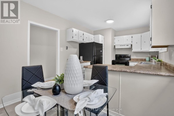 View of the kitchen from the dining area, showing white cabinets and a breakfast bar. - 914 Donovan Crescent, Whitby