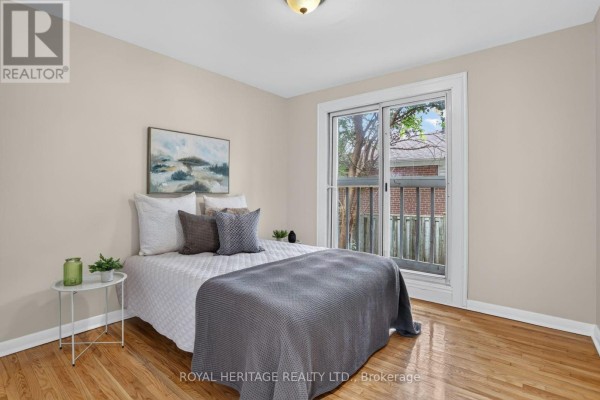 Bedroom with a double bed, hardwood floors, and a sliding glass door leading outside. - 914 Donovan Crescent, Whitby