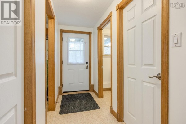 Interior hallway with wood trim, white doors, and a dark mat by the front door. - 9147 201 Highway, Nictaux