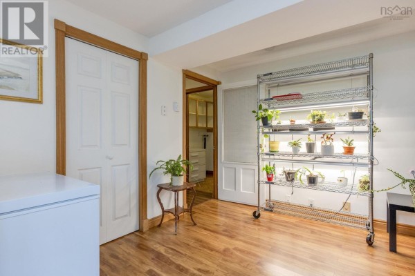 Room with wood floors, white doors, and a metal shelving unit with plants under grow lights. - 9147 201 Highway, Nictaux
