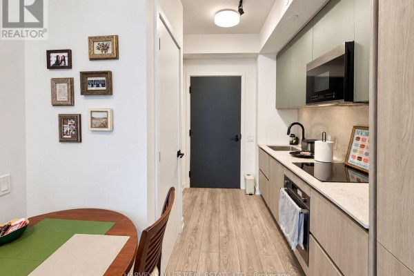 Kitchenette with light wood cabinets, grey countertop, black faucet, and framed photos on the wall. - 915 - 108 Peter Street, Toronto