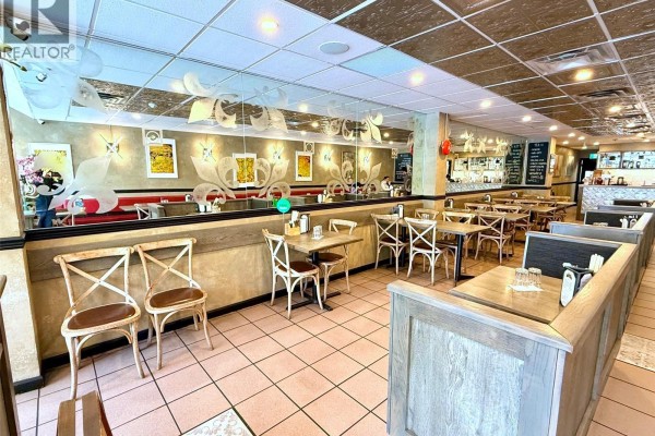 View of restaurant dining area with booths, tables, chairs, and mirrored walls. - 915 Fort St, Victoria