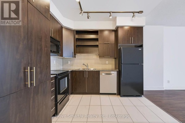 Dark wood kitchen cabinets, black appliances, and a beige tiled floor. - 917 - 50 Clegg Road, Markham