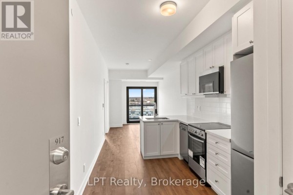 Open concept apartment interior showing kitchen, living area, and balcony. - 917 - 51 Clarington Boulevard, Clarington