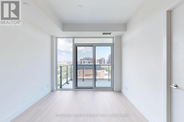 Empty room with large sliding glass doors leading to a balcony, offering city views and light wood flooring. - 917 - 6 Greenbriar Road, Toronto